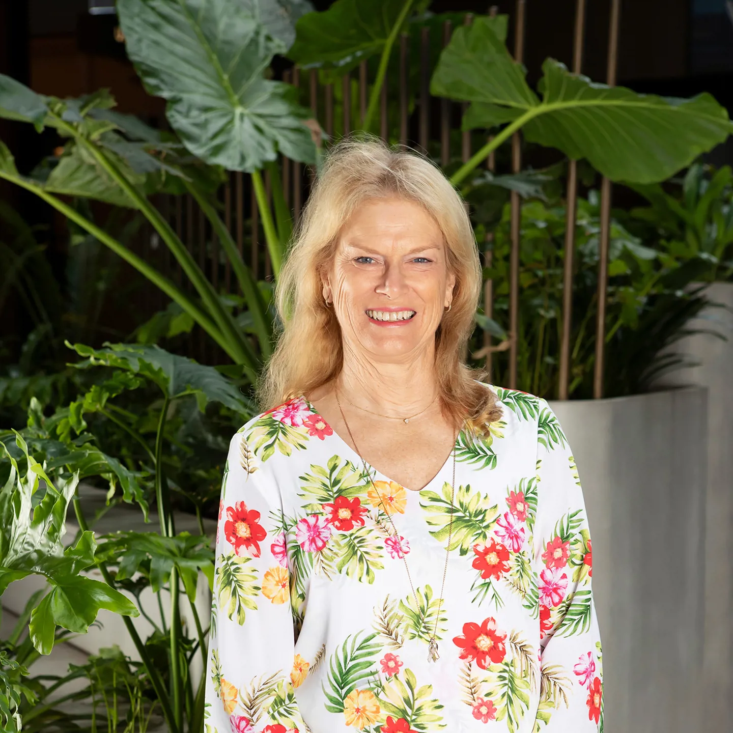 Woman with a floral shirt standing in front of plants