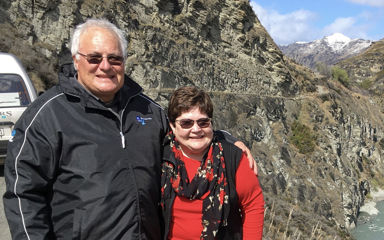 Phil and his wife Vicki standing together with a mountainside in the background
