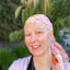A photo of Tasha after she finished chemotherapy. She is smiling and wears a pink patterned headscarf that matches her pink top