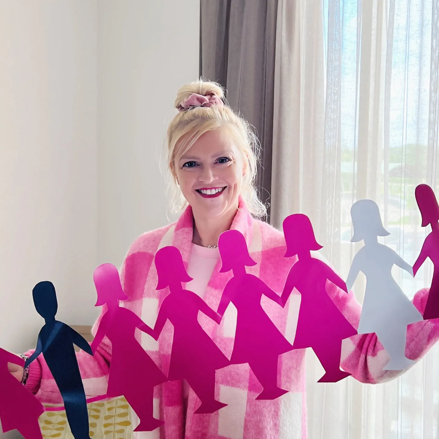 Woman standing in front of a window holding a row of pink ladies and blue men