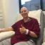 Emma in a hospital chair having chemo treatment smiling with her thumbs up
