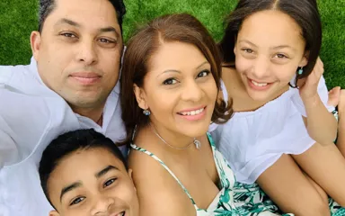 Selfie of Nadine with her son, daughter and husband all smiling and sitting on the grass