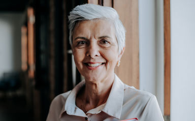 A mature woman with white hair is looking straight at the camera