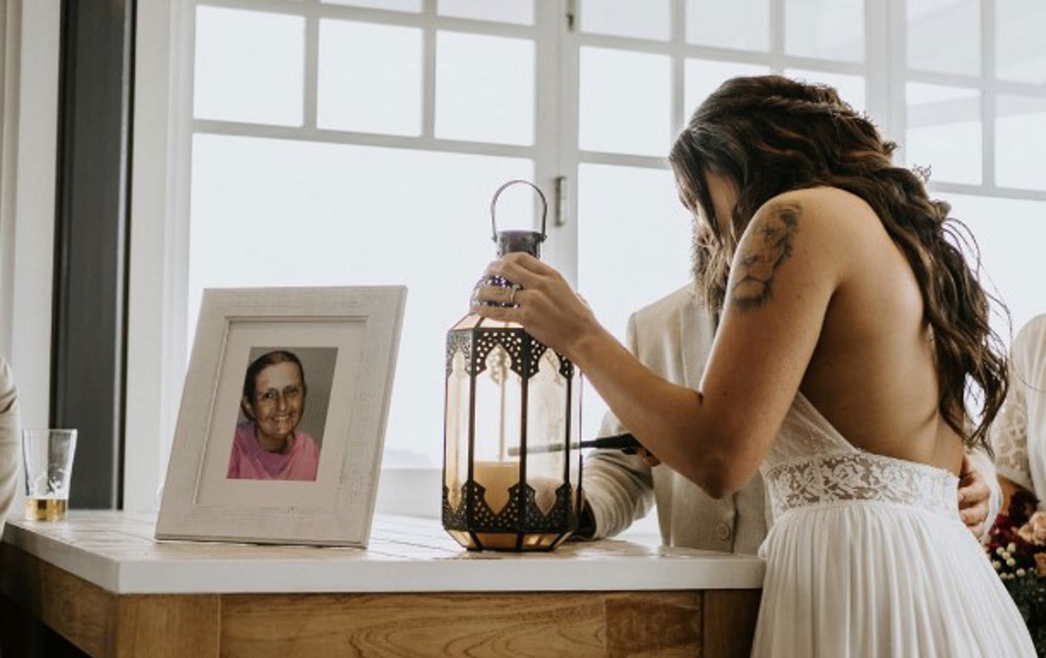 Stephanie at her wedding lighting a candle next to a portrait of her mother
