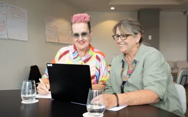 BCNA Consumer Representatives Kate and Sharon and are sitting and looking at a laptop. 