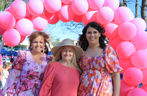 Three ladies under pink balloon garland 