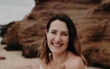 Woman with metastatic breast cancer posing on beach in white dress