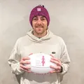 Hugh Greenwood wearing a pink beanie and holding a football