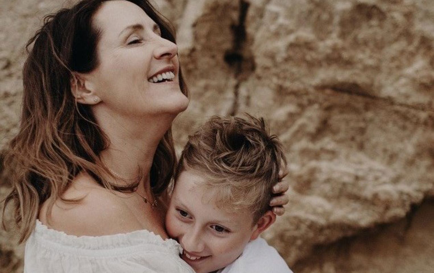 Woman with metastatic breast cancer hugging son on beach