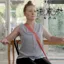 Woman exercising in her living room, sitting on a chair with a resistance band