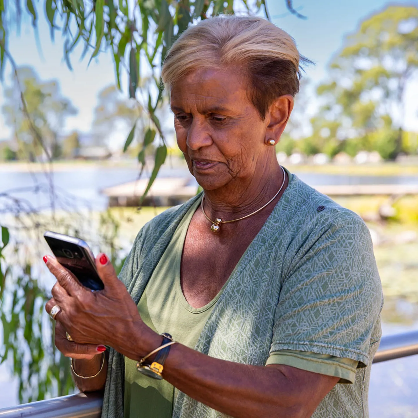 Woman standing next to a pond looking at her phone