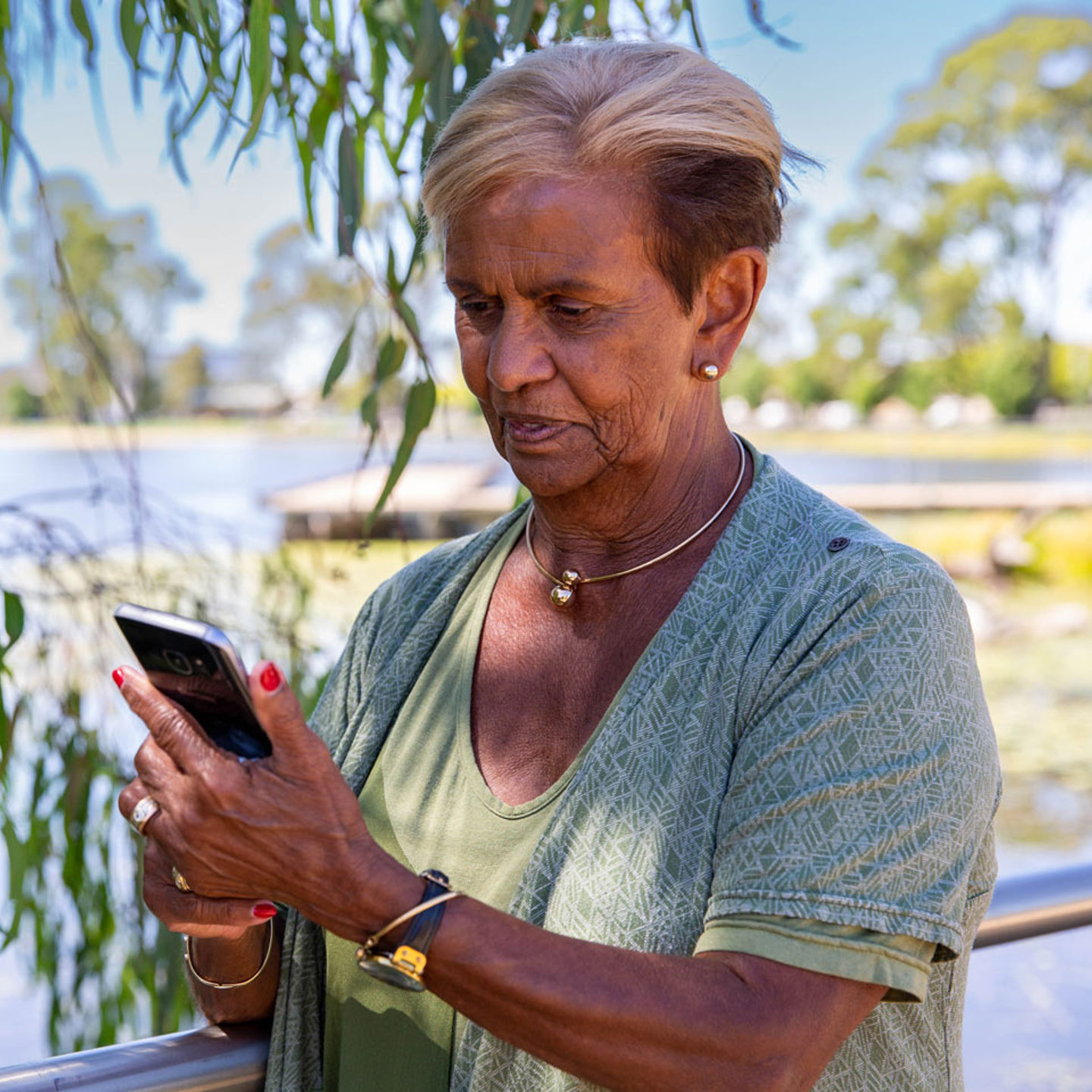 Woman standing by a pond holding her phone