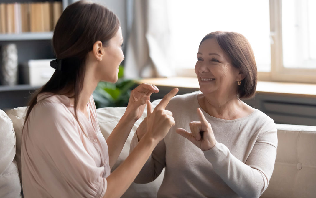 Close up mature mother and grownup daughter using sign language