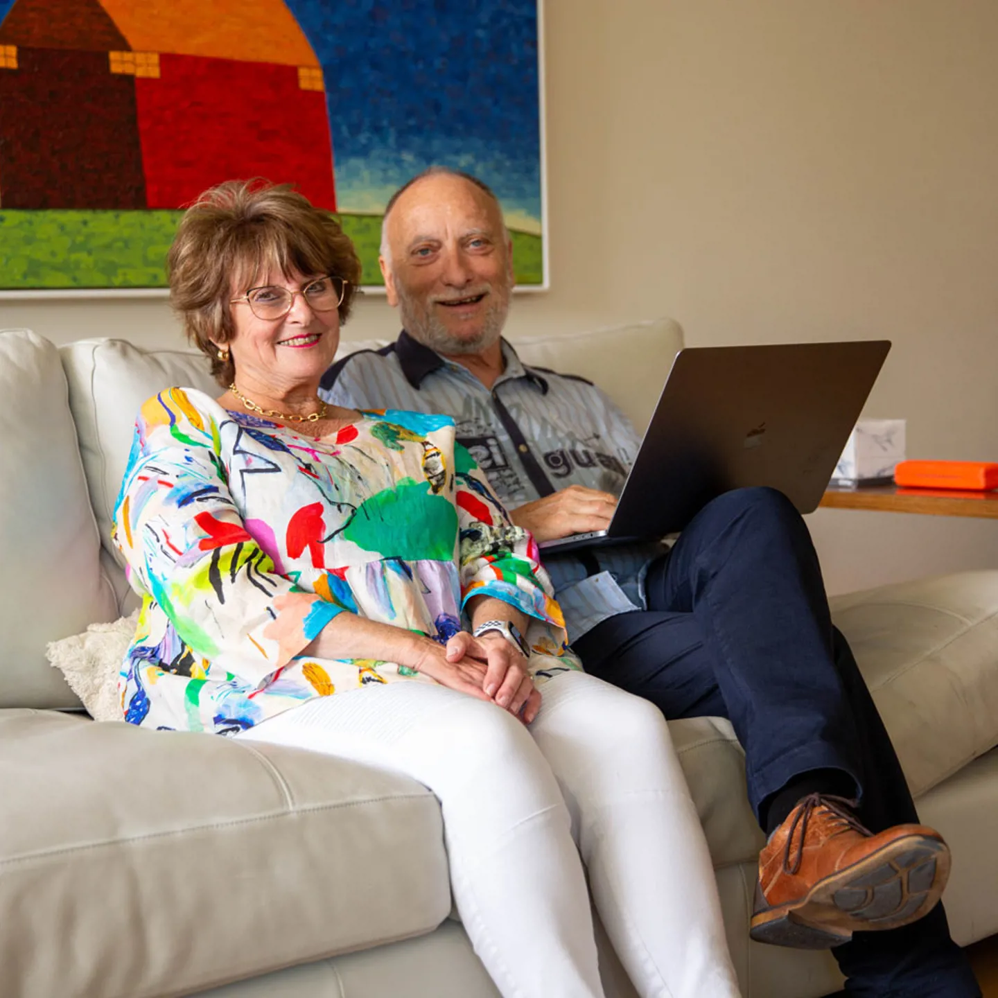 Man and woman sitting on a couch with a laptop in the man's lap