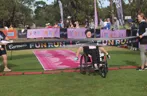 Photo of participant in wheelchair doing through the finish line at 2023 Carman's fun run